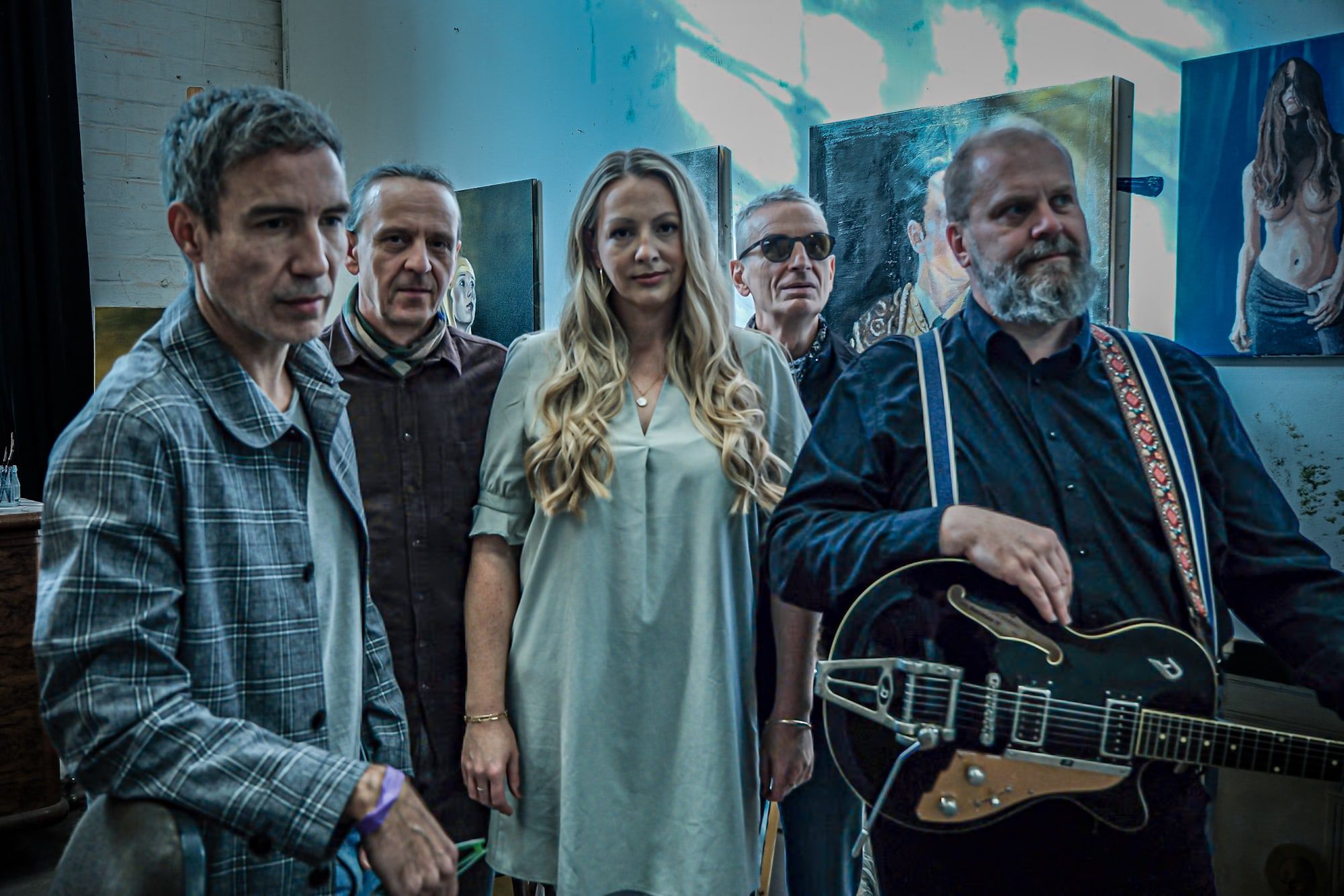 Die Band in einem Atelier mit blauem Licht und Bildern an der Wand