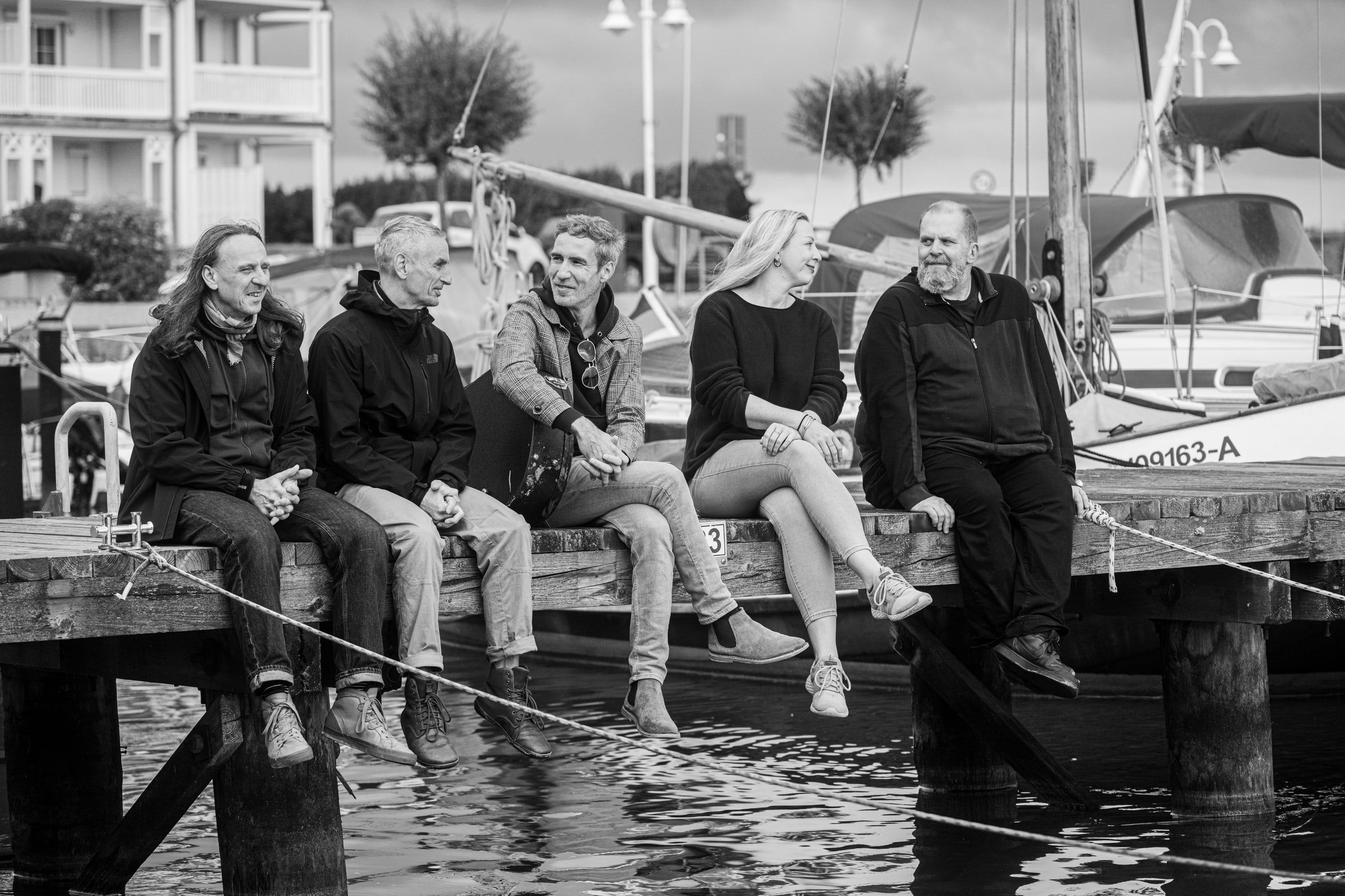 Die Band sitzt nebeneinander auf einem Steg im Hafen