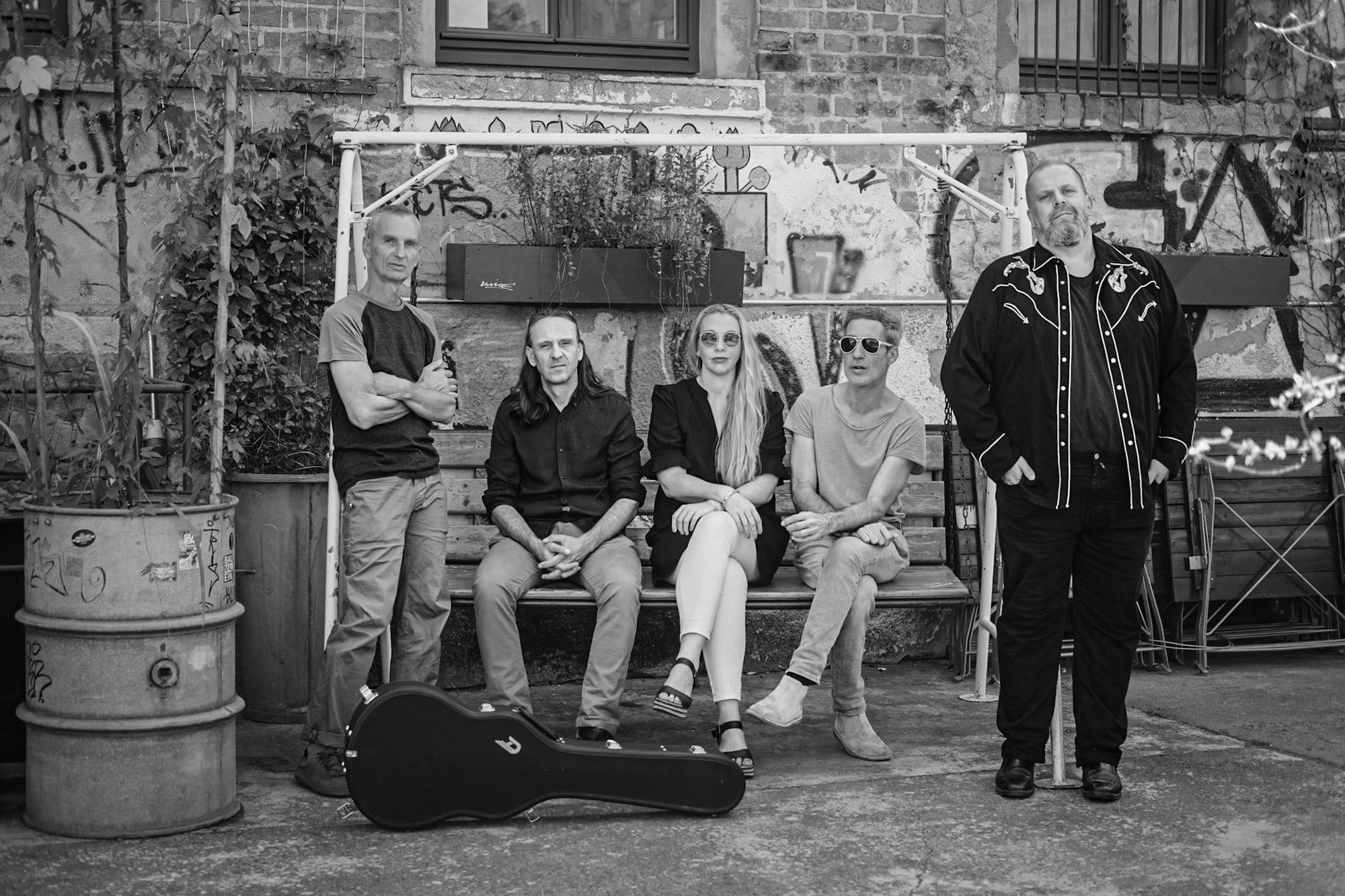 Die Band auf einer Bank in einem Leipziger Hinterhof, Gitarrenkoffer davor