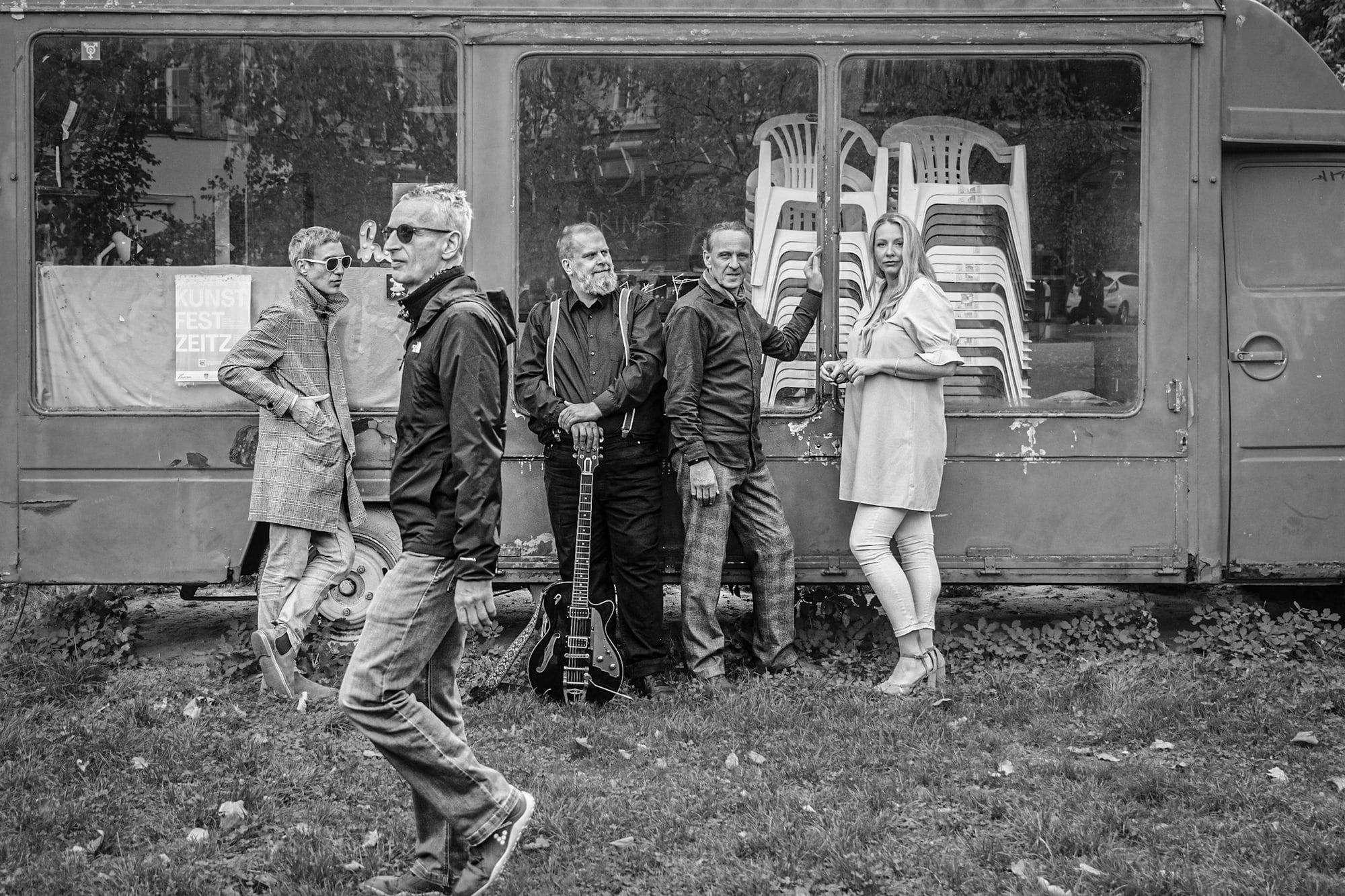 Die Band läuft an einem alten Bauwagen vorbei