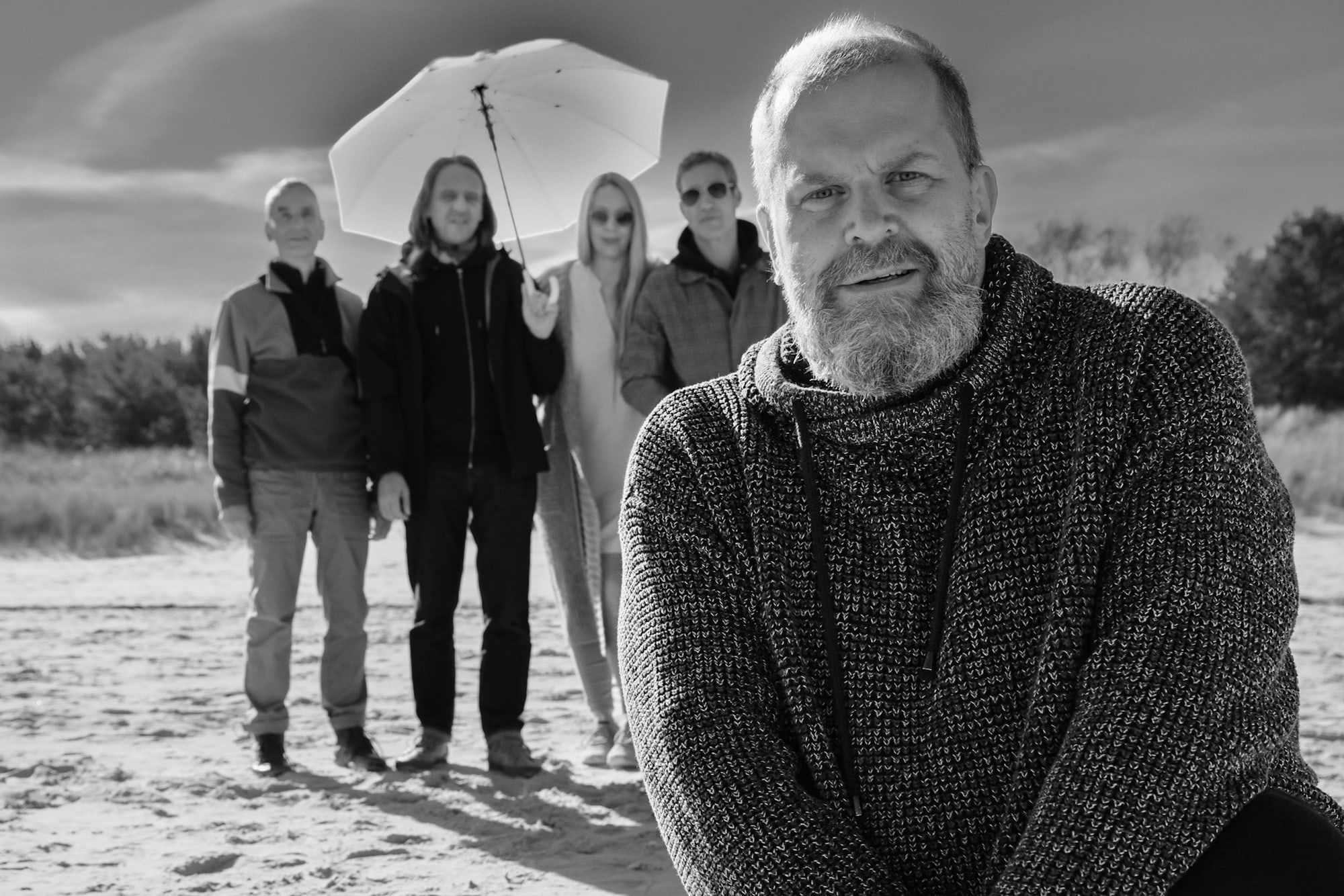 Die Band am Strand unter einem hellen Sonnenschirm, Gunter Schwarz vorn im Wollpullover